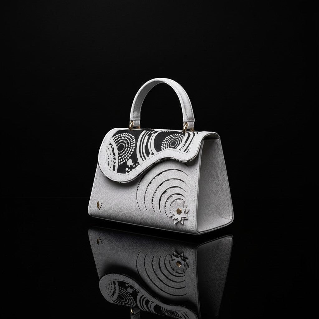 ELVI CREATION Elsha mini white vegan leather handbag with black floral appliques and spiral cut-outs.