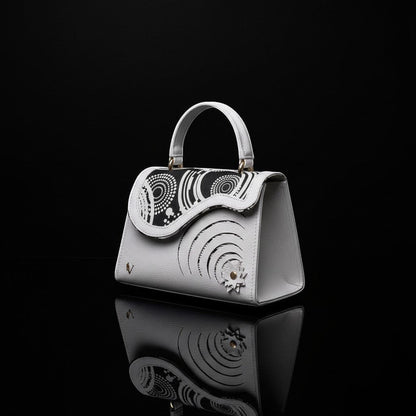 ELVI CREATION Elsha mini white vegan leather handbag with black floral appliques and spiral cut-outs.