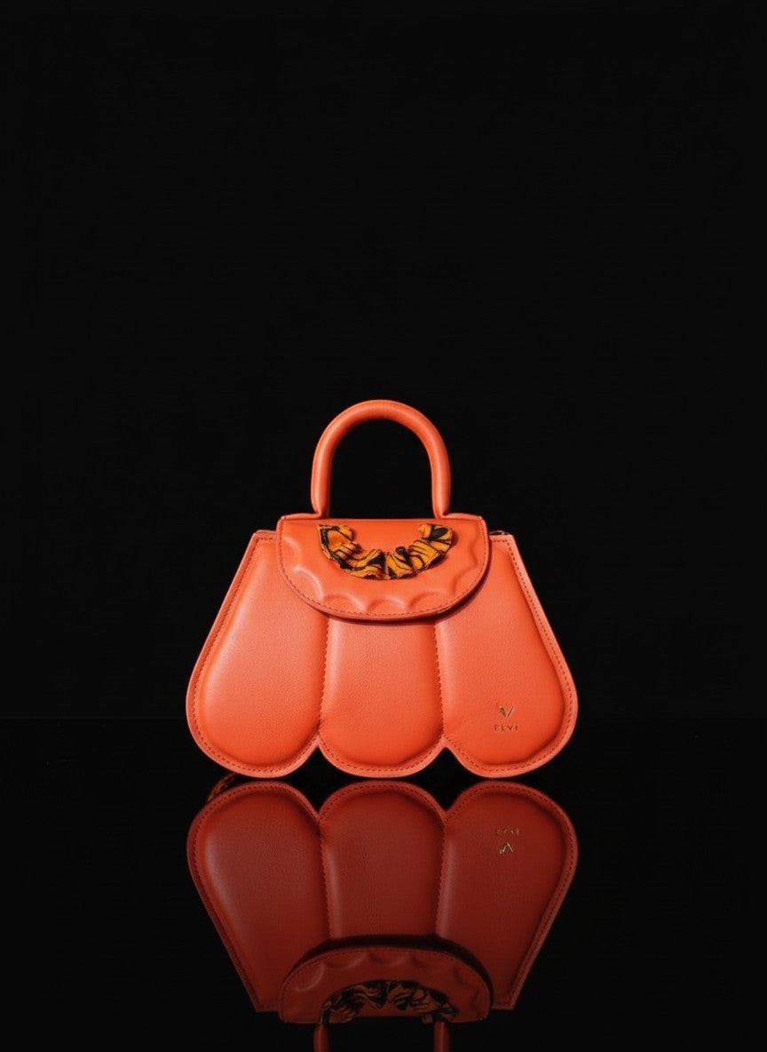 ELVI CREATION orange vegan leather Cupidon bag with sculpted petals and gold hardware. Features a patterned flap closure.