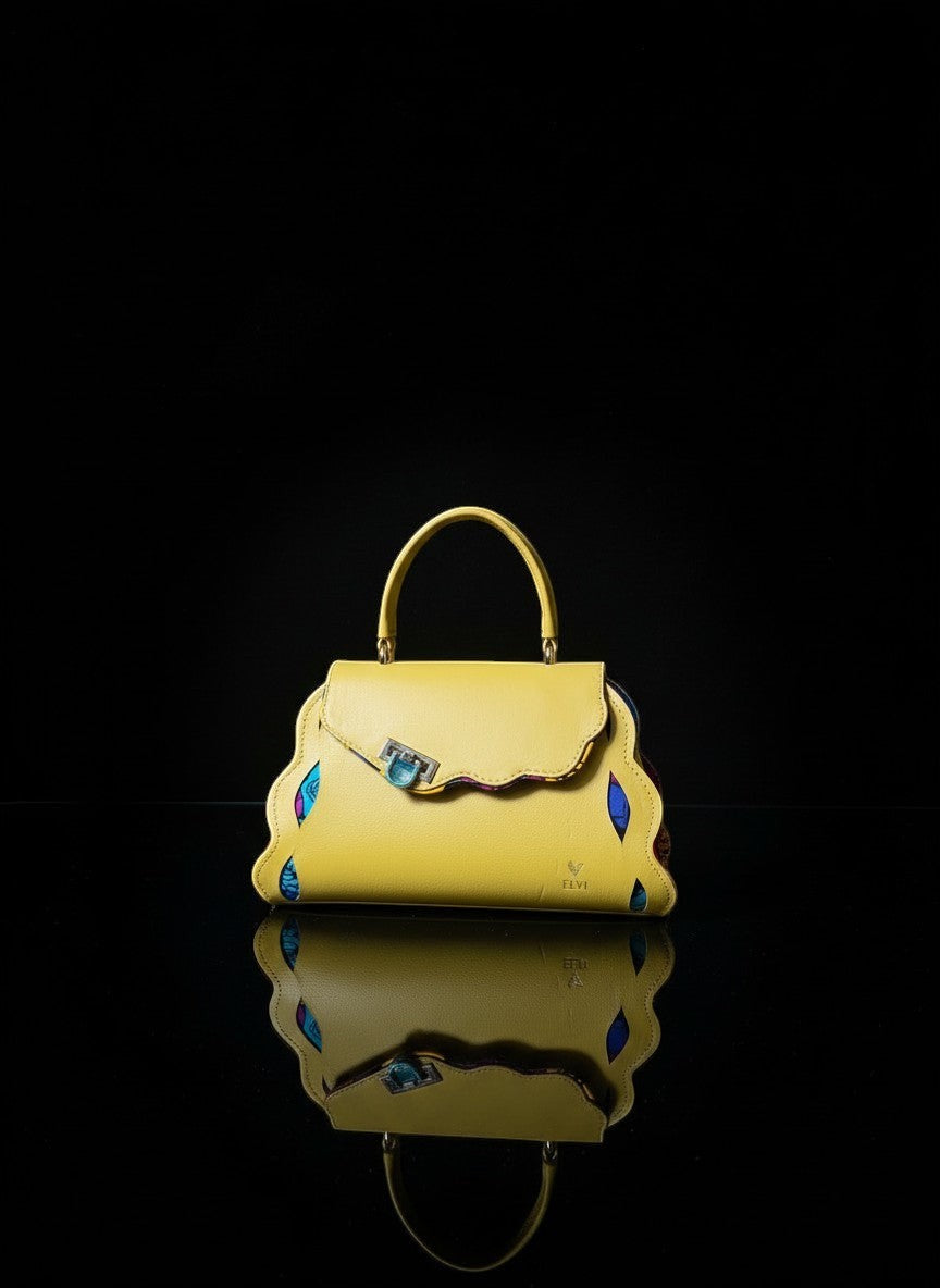 ELVI CREATION yellow vegan leather handbag with wavy edges, gold hardware, and colorful patterned lining. Sculptural and compact.